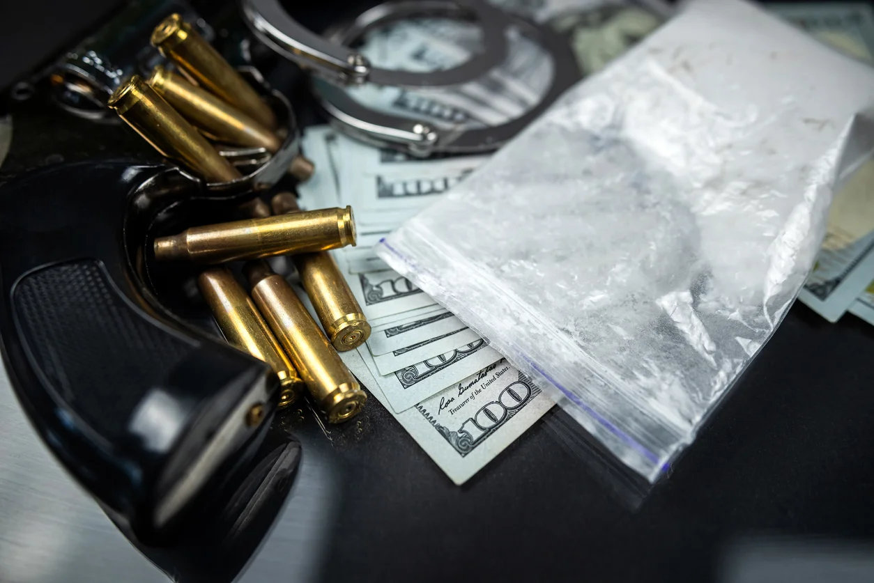 Plastic bags of cocaine or heroin and US dollar bills with handcuffs and bullets from a gun